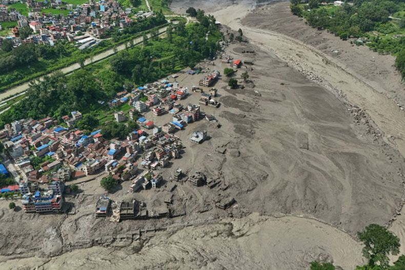 Viviendas dañadas cerca de la orilla, llena de escombros, del río Trishuli, tras las inundaciones repentinas, en el distrito de Nuwakot, Nepal, el 26 de agosto de 2026. (AP Foto/Niranjan Shrestha)