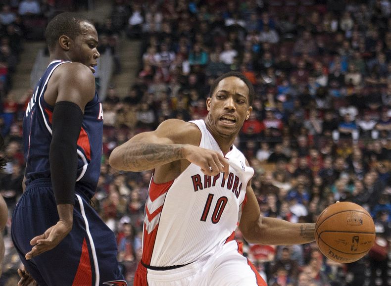 DeMar DeRozan de los Raptors de Toronto avanza con el bal&oacute;n frente a Paul Millsap de los Hawks de Atlanta el domingo 23 de marzo de 2014. (AP Foto/The Canadian Press, Nathan Denette)