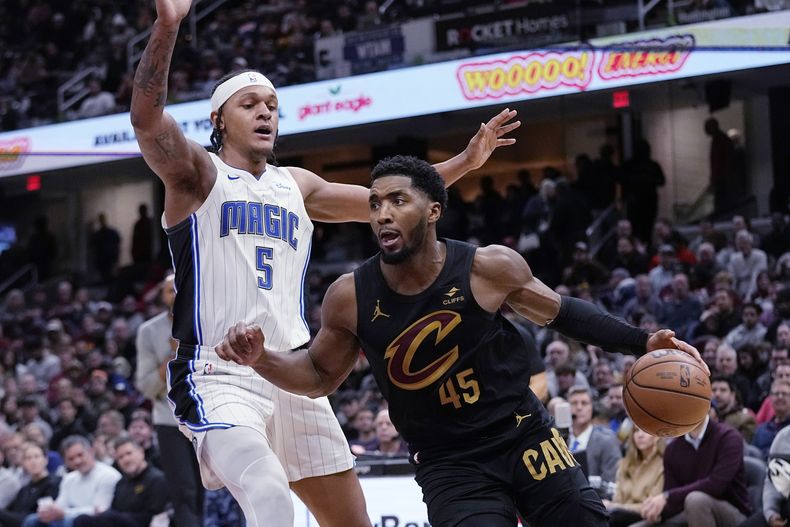 Donovan Mitchell (45), de los Cavaliers de Cleveland, supera a Paolo Banchero (5), del Magic de Orlando, durante la primera mitad del juego de baloncesto de la NBA, el miércoles 6 de diciembre de 2023, en Cleveland. (AP Foto/Sue Ogrocki)