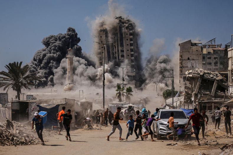 Gente corre para cubrirse durante un ataque israelí a un edificio alto en Ciudad de Gaza, el viernes 5 de septiembre de 25, después de una advertencia del ejército israelí. (AP Foto/Yousef Al Zanoun)
