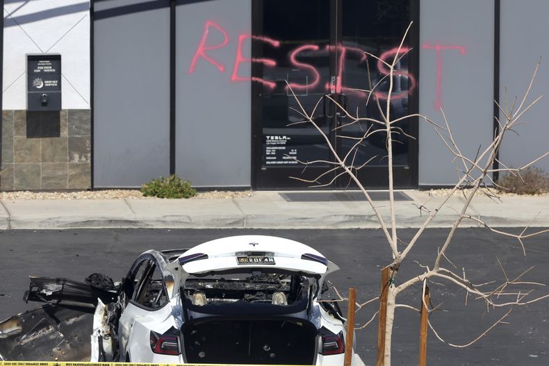 Un vehículo tesla quemado se ve en un centro de colisión de Tesla el martes 18 de marzo de 2025 en Las Vegas. El graffiti dice resistan. (Steve Marcus/Las Vegas Sun via AP)