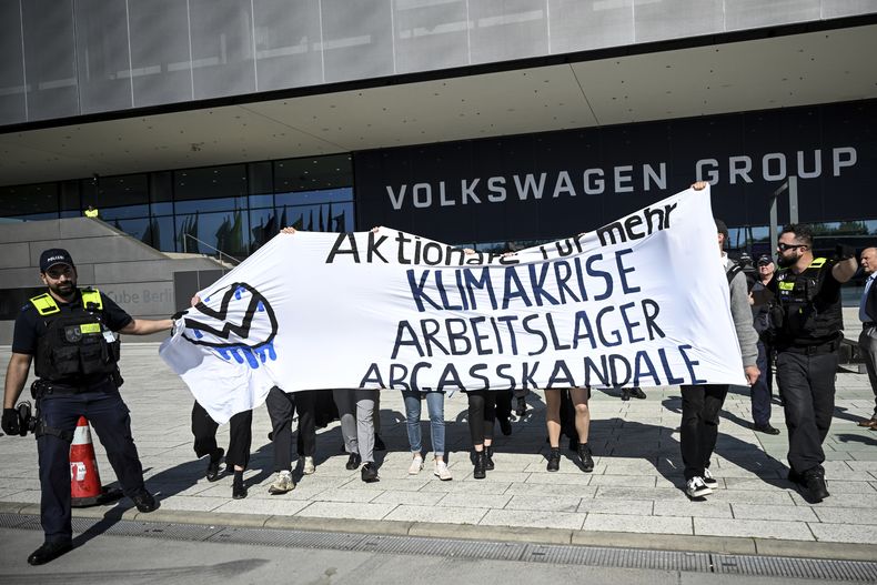 Manifestantes sostienen un letrero afuera del edificio de Volkswagen en Berlín, el miércoles 10 de mayo de 2023. (Britta Pedersen/dpa via AP)
