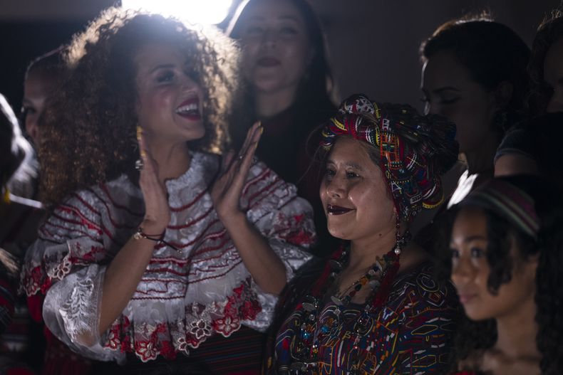 La diseñadora Elena de León, al centro a la derecha, sonríe rodeada por modelos al concluir un desfile de modas en el que se presentaron sus textiles guatemaltecos, el viernes 12 de mayo de 2023, en Brownsville, Texas. De León, nacida en Guatemala, combinó técnicas indígenas de tejido, diseño moderno de ropa y colorida historia de su país natal en el desfile. La presentación ofreció una muestra no sólo de la visión artística de De León, sino un trabajo de madres guatemaltecas, incluidas algunas que viven en Estados Unidos y otras que se quedaron en su país para apoyar a sus familias. (AP Foto/Julio Cortez)