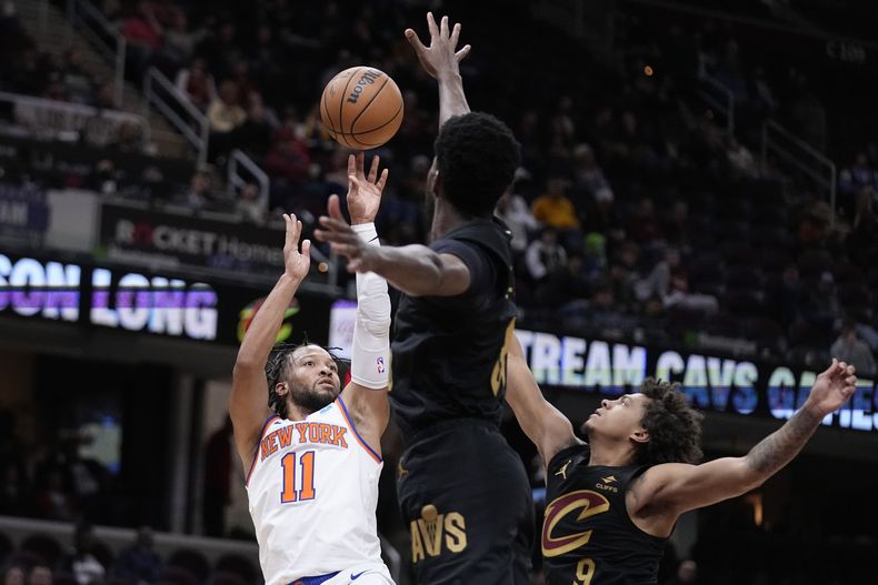 Jalen Brunson, base de los Knicks de Nueva York, dispara frente a Damian Jones (centro) y Craig Porter, de los Cavaliers de Cleveland, en el partido del martes 31 de octubre de 2023 (AP Foto/Sue Ogrocki)