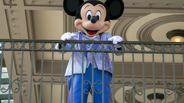 ARCHIVO - Un actor vestido como Mickey Mouse saluda a visitantes en la entrada del Parque Temático Magic Kingdom en Walt Disney World Resort, el 18 de abril de 2022, en Lake Buena Vista, Florida. Winnie the Pooh y Mickey Mouse han entrado recientemente en el dominio público, lo que hace posible que los artistas los usen libremente. (Foto AP/Ted Shaffrey, archivo)