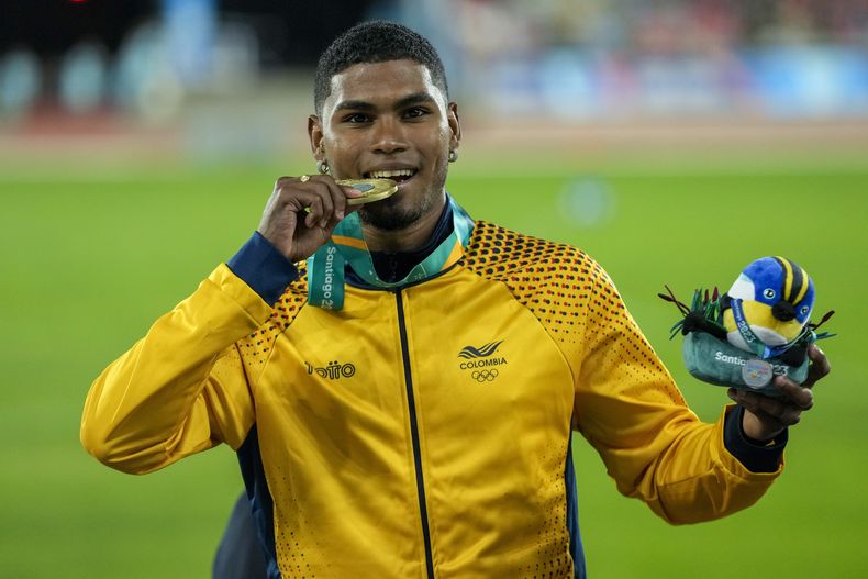 El colombiano Arnovis Dalmero muerde su medalla de oro tras ganar el salto largo del atletismo de los Juegos Panamericanos en Santiago, Chile, el martes 31 de octubre de 2023. (AP Foto/Esteban Félix)