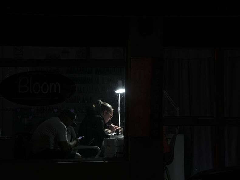 Una mujer hace un trabajo de manicura bajo una lámpara con un foco recargable durante un corte de luz en Quito, Ecuador, el miércoles 11 de diciembre de 2024, ante la crisis energética y el racionamiento eléctrico de varias horas diarias que las autoridades han atribuido a una sequía. El gobierno del presidente Daniel Noboa anunció que los cortes quedarían suspendidos desde el 20 de diciembre durante las fiestas navideñas y de fin de año. (AP Foto/Dolores Ochoa)