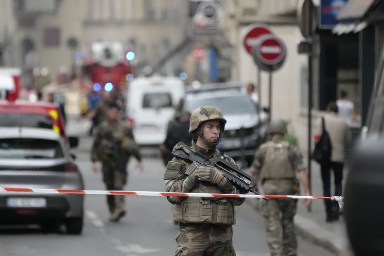 Un soldado custodia una calle mientras bomberos extinguen un incendio, el 21 de junio de 2023 en París. (AP Foto/Christophe Ena)