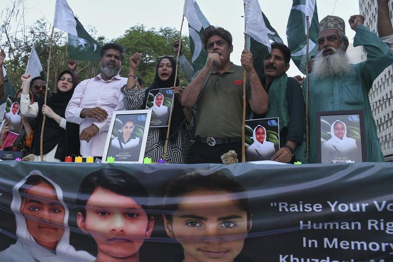 Miembros de una sociedad civil muestran retratos de niños que murieron en el ataque contra un autobús escolar en Khuzdar, durante una marcha para condenar el ataque, en Karachi, Pakistán, el miércoles 21 de mayo de 2025. (AP Foto/Ali Raza)