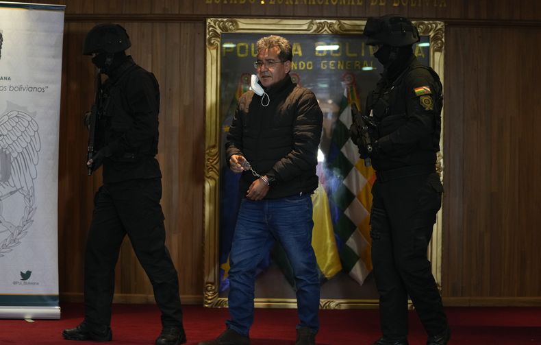 ARCHIVO - La policía escolta al exdirector antidrogas de la policía boliviana, coronel Maximiliano Dávila, mientras es presentado a la prensa en una oficina de comando de la policía boliviana después de ser arrestado acusado de estar vinculado con una red de narcotráfico en La Paz, Bolivia, domingo 23 de enero de 2022. (AP Foto/Juan Karita, Archivo)