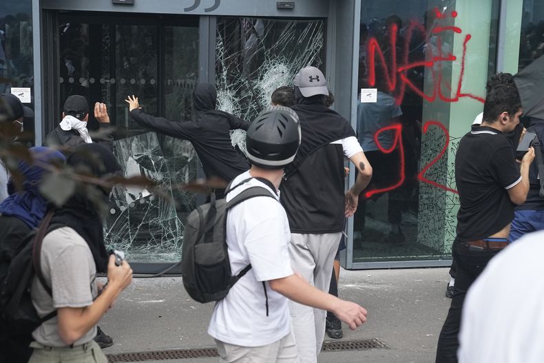 ARCHIVO - Jóvenes revientan un cristal tras una marcha por Nahel, el jueves 29 de junio de 2023 en Nanterre, a las afueras de París. En total, más de 3.600 personas han sido detenidas en los disturbios en Francia desde la muerte de Nahel el 27 de junio, con una edad media de 17, según el Ministerio del Interior. (AP Foto/Michel Euler, Archivo)