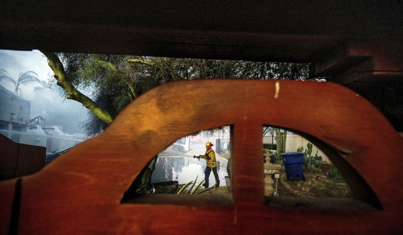 Un bombero limpia con una manguera el garaje de la casa de Noel Piri que fue destruida por el incendio de Hawarden en Riverside, California, el domingo 21 de julio de 2024. (Terry Pierson/The Orange County Register vía AP)