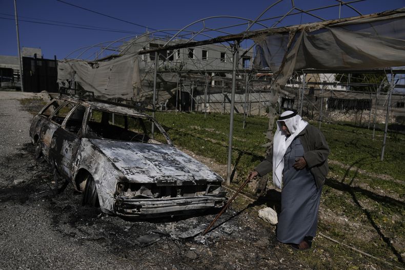 Un palestino junto a un auto incendiado tras el ataque perpetrado por presuntos colonos israelíes en la aldea de Jinsafut, en Cisjordania, el martes 21 de enero de 2025. (AP Foto/Majdi Mohammed)