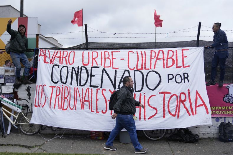 Opositores al expresidente Álvaro Uribe cuelgan carteles de protesta afuera del tribunal el día en que fue sentenciado a 12 años de arresto domiciliario por manipulación de testigos y soborno en Bogotá, Colombia, el viernes 1 de agosto de 2025. (AP Foto/Fernando Vergara)