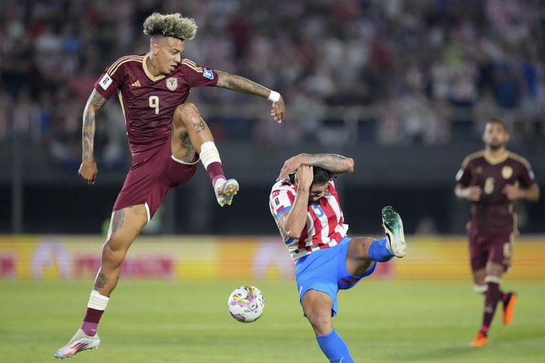 El venezolano Jhonder Cádiz (izquierda) y el paraguayo Omar Alderete pugnan por el balón en el partido por las eliminatorias del Mundial, el martes 15 de octubre de 2024, en Asunción. (AP Foto/Jorge Saenz)
