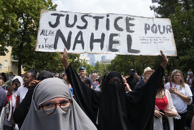 ARCHIVO - Una mujer lleva un cartel con el mensaje Justicia para Nahel durante una marcha en memoria de Nahel Merzouk, de 17 años, que murió baleado por la policía, el jueves 29 de junio de 2023 en Nanterre, a las afueras de París. (AP Foto/Michel Euler, Archivo)