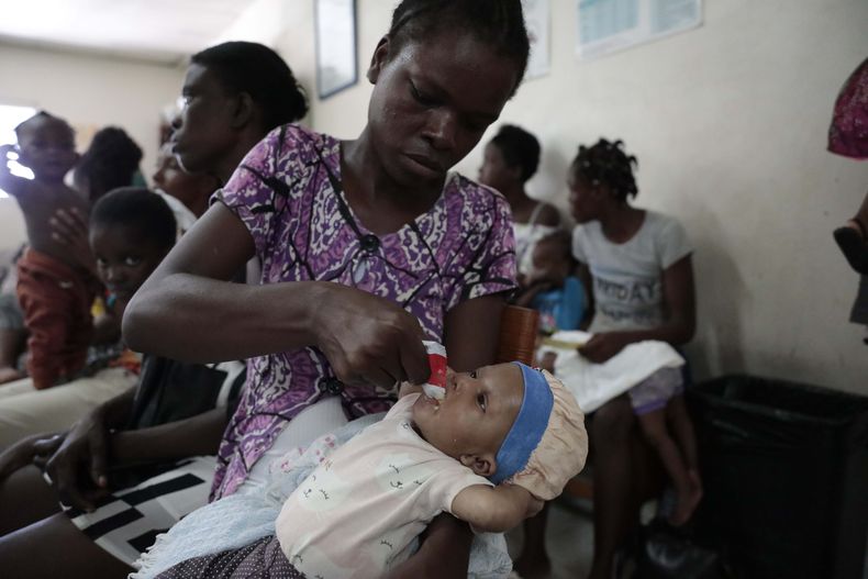 Cetout Widlore alimenta a su hija Naomie Cesar, de siete meses, luego que personal de salud revisara el estado de salud de la bebé en el Centro Gheskio, en Puerto Príncipe, Haití, el viernes 14 de julio de 2023. (AP Foto/Odelyn Joseph)