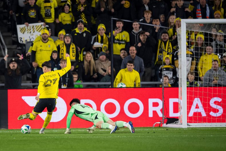 Max Arfsten (27), delantero de el Columbus Crew, patea el balón mientras Roman Celentano (18), portero de FC Cincinnati, intenta defender durante la primera mitad del Juego 2 de la primera ronda de los playoffs de la Conferencia Este del fútbol de la MLS, el domingo 2 de noviembre de 2025, en Columbus. (AP Photo/Tanner Pearson)
