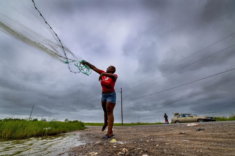 Latia Ancar practica con una amiga a lanzar una red bajo el cielo oscurecido antes de la tormenta tropical Bertha mientras esperan a la marejada ciclónica de la tormenta con la esperanza de que lleve más peces, unas 50 millas al sur de Nueva Orleans, el 22 de julio de 2026. (Chris Granger/The Times-Picayune/The New Orleans Advocate via AP)