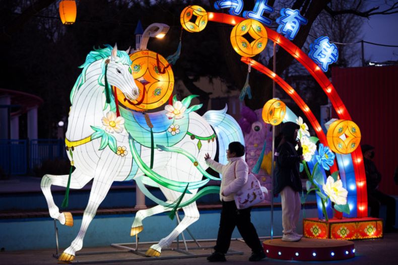 Visitantes pasan junto a la figura de un caballo iluminado antes de las celebraciones del Año Nuevo Lunar en un parque de diversiones a las afueras de Beijing, China, el sábado 14 de febrero de 2026. (AP Foto/Vincent Thian)