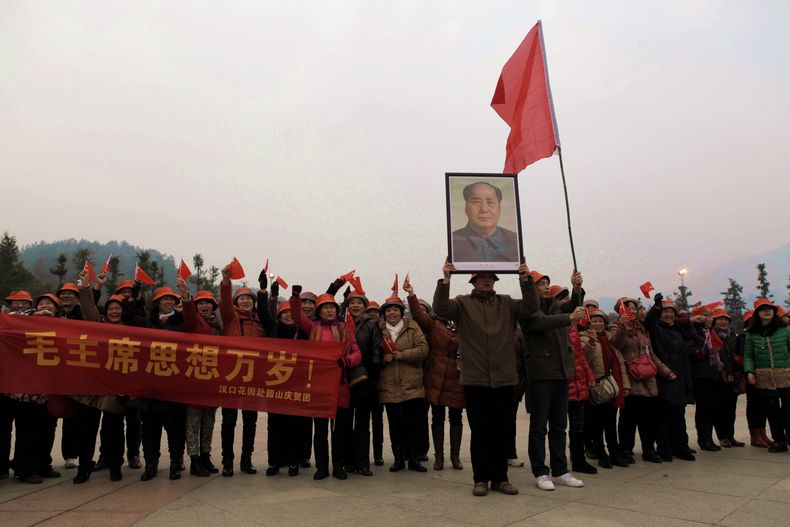 Unas personas ondean un cartel y sostienen una foto de Mao Tse-tung en Shaoshan, pueblo natal del l&iacute;der chino, en Hunan, en el sur de China, el 26 de diciembre de 2013, en conmemoraci&oacute;n de los 120 a&ntilde;os del nacimiento de Mao. (Foto AP)
