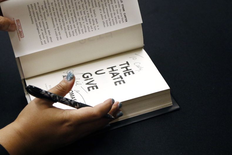 Angie Thomas, de 30 años, residente de Jackson, Mississippi, cuyo libro, The Hate U Give, ha estado en la lista nacional de los libros más vendidos para adultos jóvenes durante 82 semanas, termina de autografiar una copia de su libro en una recepción en Jackson, Mississippi el 10 de octubre de 2018. (Foto AP/Rogelio V. Solis)