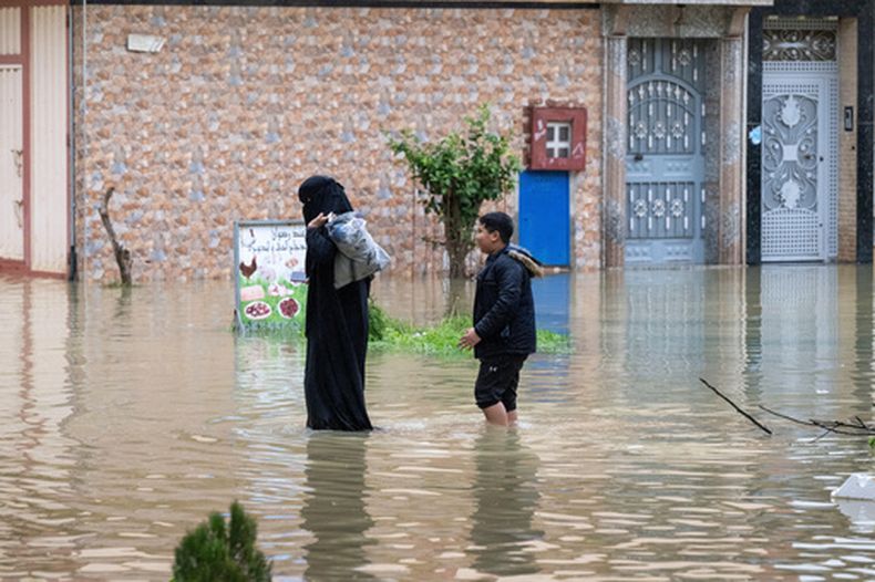 Una madre y su hijo evacuan una calle inundada tras fuertes lluvias en Ksar El Kebir, Marruecos, el viernes 30 de enero de 2026. (Foto AP)