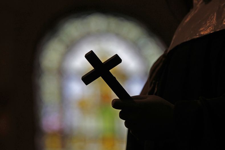 ARCHIVO - La silueta de un crucifijo puede apreciarse frente a un vitral dentro de un templo católico, el 1 de diciembre de 2012, en Nueva Orleans. (AP Foto/Gerald Herbert, archivo)