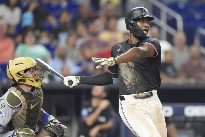 Jesús Sánchez, de los Marlins de Miami, golpea con el bate en el casco al receptor de los Mets de Nueva York, Tomás Nido, durante la octava entrada del juego de béisbol, el viernes 17 de mayo de 2024, en Miami. (AP Foto/Wilfredo Lee)