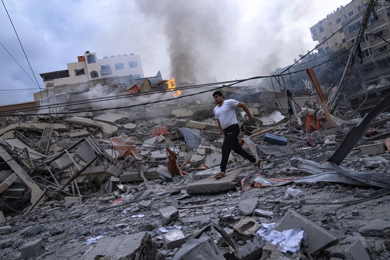 Palestinos caminan entre los escombros que dejaron los ataques israelíes contra algunas zonas de un vecindario en la Ciudad de Gaza, el martes 10 de octubre de 2023. Hamas, el grupo islamista que gobierna la Franja de Gaza, llevó a cabo el sábado un ataque sin precedentes contra Israel, dejando más de 1.000 muertos y varios secuestrados. Israel respondió con intensos bombardeos contra el territorio, matando a cientos de palestinos. (AP Foto/Fatima Shbair)