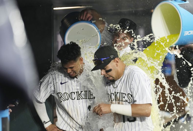 El venezolano Ezequiel Tovar (izquierda) y el mexicano Alan Trejo son empapados por sus compañeros tras la victoria sobre los Marlins de Miami, el jueves 25 de mayo de 2023 (AP Foto/David Zalubowski)