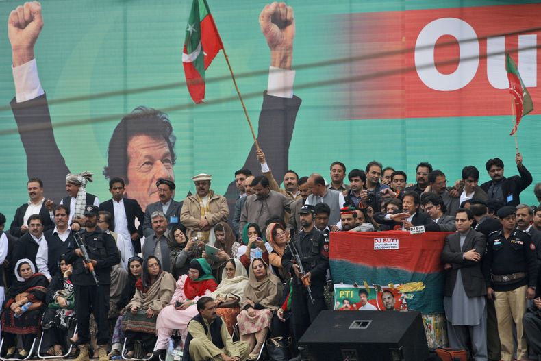 El pol&iacute;tico paquistan&iacute; y estrella del cricket Imran Khan, l&iacute;der del partido Tehreek-e-Insaf, al centro a la derecha con micr&oacute;fono en mano y desde un estrado, da un discurso rodeado de agentes de seguridad e integrantes del part