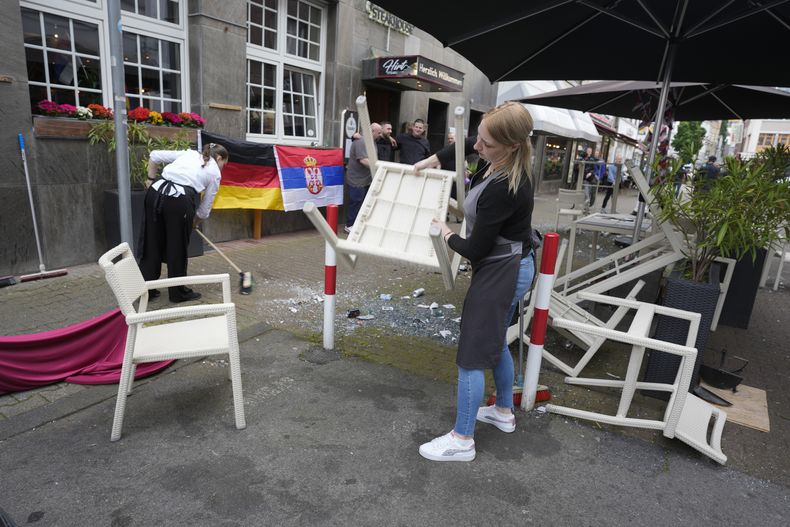 Personas limpian la basura después de los enfrentamientos de los fanáticos antes del partido del Grupo C entre Serbia e Inglaterra en el torneo de fútbol Euro 2024 en Gelsenkirchen, Alemania, el domingo 16 de junio de 2024. (Foto AP/Markus Schreiber)