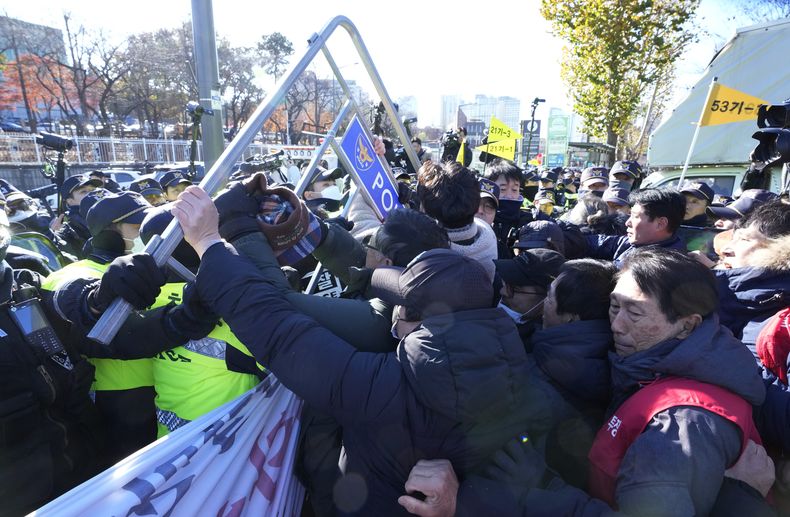 Dueños de granjas caninas chocan con policías frente a la oficina presidencial durante una protesta contra un proyecto de ley encabezado por el gobierno para prohibir el consumo de carne de perro, en Seúl, Corea del Sur, el jueves 30 de noviembre de 2023. (AP Foto/Ahn Young-joon)