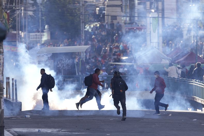 Simpatizantes del expresidente Evo Morales huyen de los gases lacrimógenos lanzados por la policía durante enfrentamientos cerca de las oficinas del Tribunal Electoral, el viernes 16 de mayo de 2025, en La Paz, Bolivia. (Foto AP/Juan Karita)