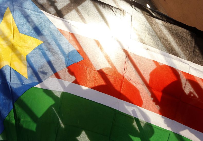En esta imagen de archivo, sursudaneses, vistos a través de la tela de una bandera de Sudán del Sur, esperan para votar en la capital del país, Juba, el 9 de enero de 2011. (AP Foto/Jerome Delay, archivo)