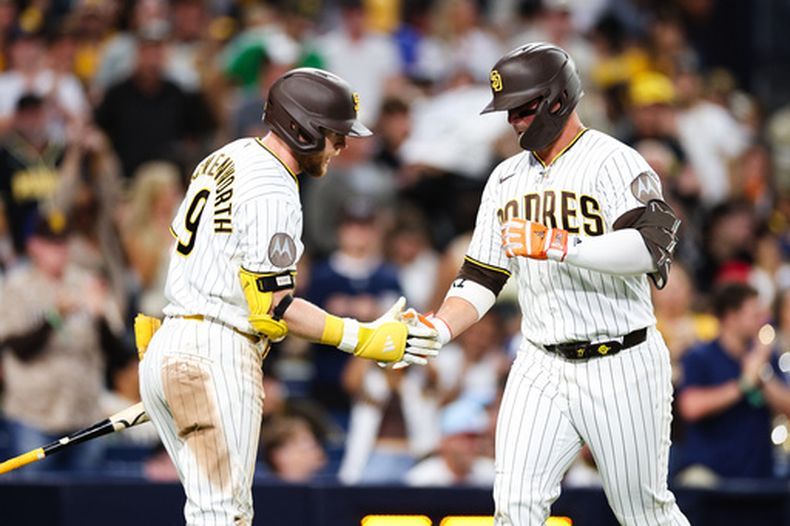 Ty France, derecha, de los Padres de San Diego, es felicitado por Jake Cronenworth, izquierda, después de batear un cuadrangular solitario contra los Azulejos de Toronto durante la sexta entrada del juego de béisbol de Grandes Ligas, el sábado 11 de julio de 2026, en San Diego. (AP Foto/Derrick Tuskan)