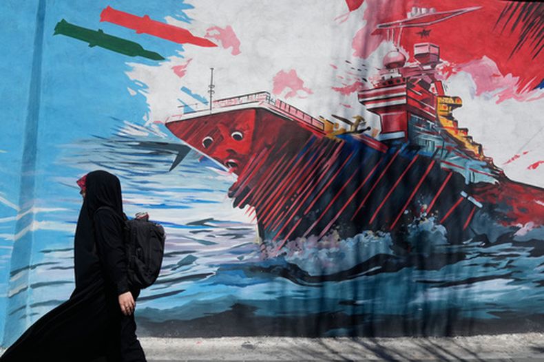Una mujer pasa junto a un mural que muestra un portaaviones estadounidense bajo ataque en el centro de Teherán, Irán, el lunes 8 de junio de 2026. (AP Foto/Vahid Salemi)