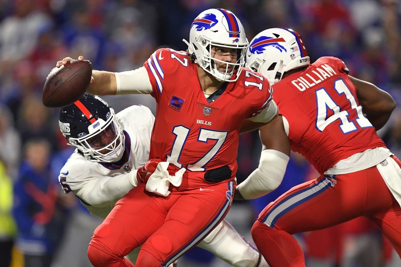 El quarterback Josh Allen (17), de los Bills de Buffalo, trata de evadir la tacleada del linebacker Kayvon Thibodeaux, izquierda, de los Giants de Nueva York, en duelo en Orchard Park, Nueva York, el domingo 15 de octubre de 2023. (AP Foto/Adrian Kraus)