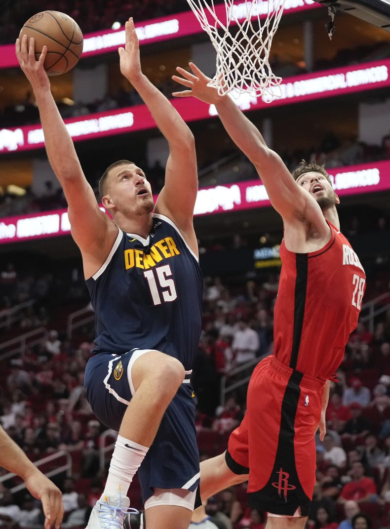 El pívot de los Nuggets de Denver, Nikola Jokic (15), dispara mientras el pívot de los Rockets de Houston, Alperen Sengun, defiende durante la primera mitad de un partido de baloncesto de la NBA, el domingo 13 de abril de 2025, en Houston. (AP Foto/Eric Christian Smith)
