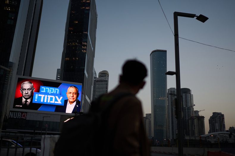 Un peatón pasa ante una valla publicitaria con la imagen del primer ministro de Israel, Benjamin Netanyahu, a la izquierda, y su principal rival, el candidato opositor Gadi Eisenkot, con un mensaje en hebreo que dice la carrera está ajustada, el viernes 23 de octubre de 2026 en Tel Aviv, Israel. (AP Foto/David Goldman)