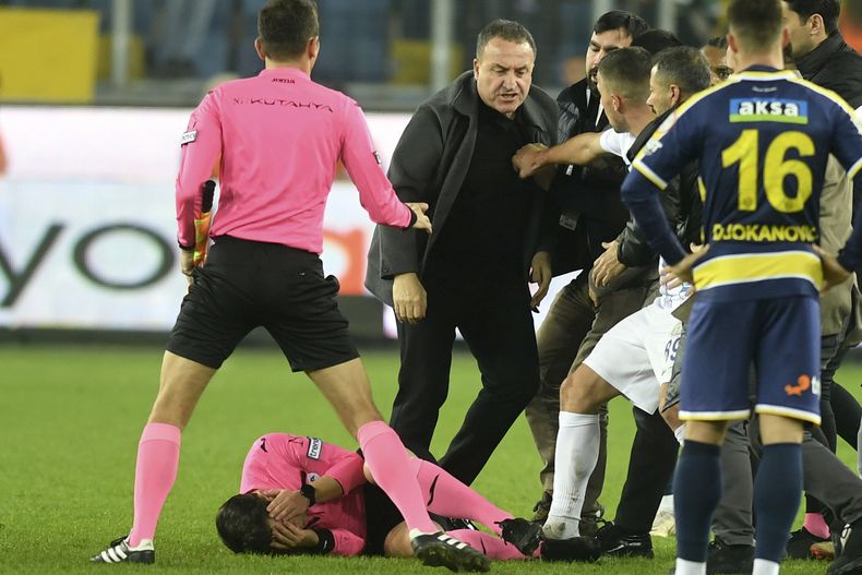 En esta imagen de archivo, el árbitro Halil Umut Meler se sujeta el rostro mientras está tirado sobre el piso luego de recibir un golpe del presidente del MKE Ankaragucu, Faruk Koca (centro), al final de un partido de la Superliga turca frente al Caykur Rizespor, en Ankara, el 11 de diciembre de 2023. (Abdurrahman Antakyali/Depo Photos vía AP, archivo)