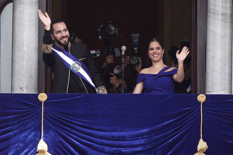 El presidente de El Salvador, Nayib Bukele y la primera dama Gabriela Roberta Rodríguez saludan desde un balcón después de su investidura para un segundo mandato, el sábado 1 de junio de 2024, en San Salvador. (AP Foto/Salvador Melendez)