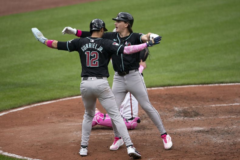 Lourdes Gurriel Jr. (12), de los Diamondbacks de Arizona, celebra con su compañero Jake McCarthy, derecha, después de anotar una carrera en el juego de béisbol en contra de los Orioles de Baltimore, el domingo 12 de mayo de 2024, en Baltimore. (AP Foto/Jose Luis Magana)