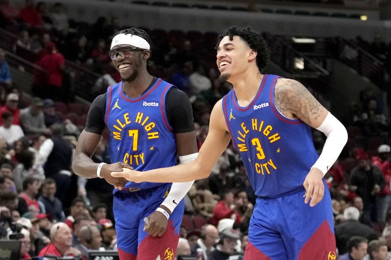 Reggie Jackson (7), base de los Nuggets de Denver, celebra con su compañero Julian Strawther la victoria sobre los Bulls de Chicago, el martes 12 de diciembre de 2023 (AP Foto/Charles Rex Arbogast)