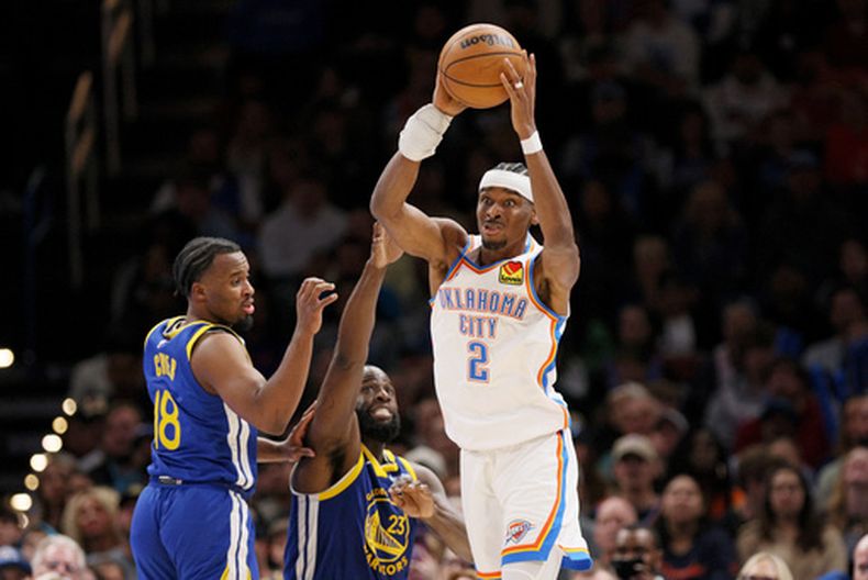 Shai Gilgeous-Alexander, del Thunder de Oklahoma City, busca enviar un pase frente a Draymond Green, de los Warriors de Golden State, el sábado 7 de marzo de 2026 (AP Foto/Nate Billings)