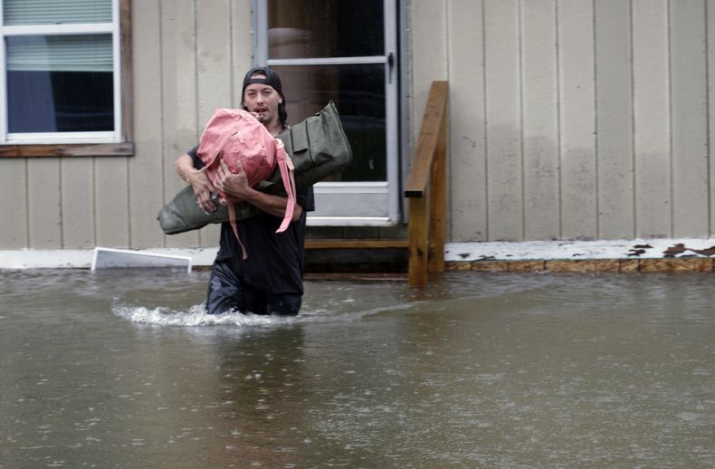 Un hombre carga objetos personales por una zona inundada desde una casa en Bridgewater, Vermont, el lunes 10 de julio de 2023. Las fuertes lluvias anegaron zonas del nordeste de Estados Unidos, donde destruyeron carreteras, forzaron evacuaciones y paralizaron parte del tráfico aéreo. (AP Foto/Hasan Jamali)