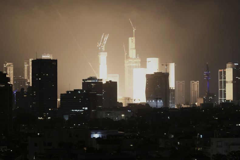 Una explosión causada por el impacto de un proyectil ilumina el horizonte de Tel Aviv, Israel, la mañana del sábado 14 de junio de 2025. (AP Foto/Leo Correa)