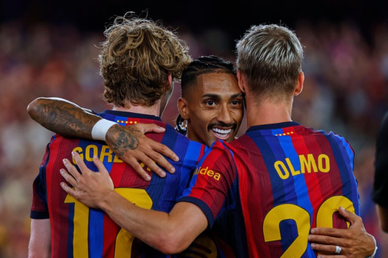 Anthony Gordon, del Barcelona, celebra con sus compañeros Raphinha, centro, y Dani Olmo, derecha, después de que Florian Lejeune, del Rayo Vallecano, marcara en su propia portería en partido de fútbol de La Liga española, el lunes 31 de agosto de 2026, en Barcelona, España. (AP Foto/Joan Monfort)