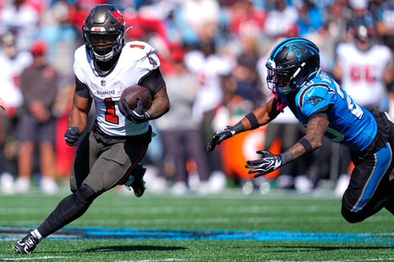 Kenny Gainwell (1), de los Buccaneers de Tampa Bay, corre dejando atrás a Zakee Wheatley (20), de los Panthers de Carolina, durante la primera mitad de un partido de fútbol americano de la NFL en Charlotte, Carolina del Norte, el domingo 25 de octubre de 2026. (Foto AP/Erik Verduzco)